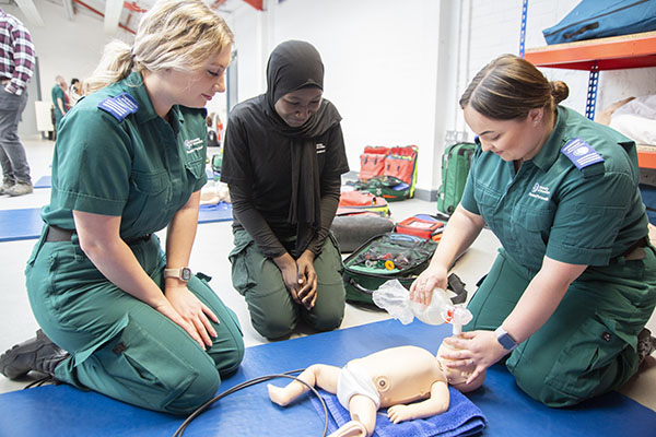 Three students performing CPR on a baby dummy