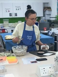 student in a blue apron mixing food ingredients