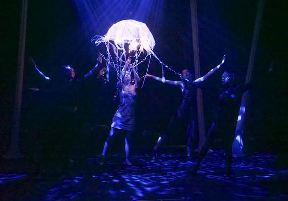 A girl is dancing with a large plastic jellyfish