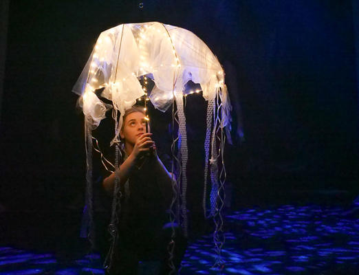 A girl is dancing with a large plastic jellyfish