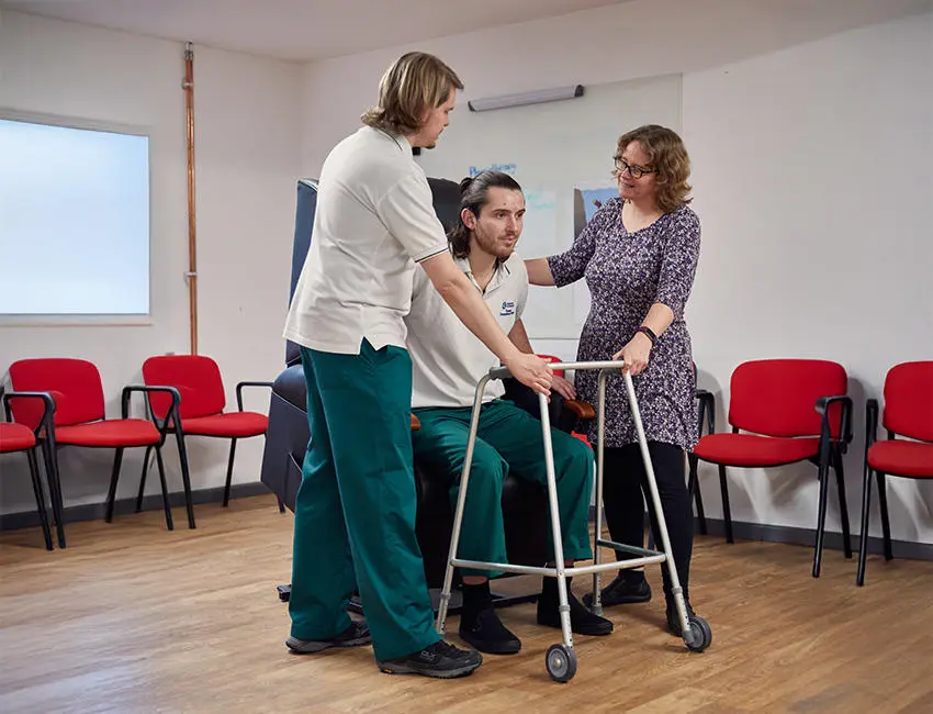 An occupational therapy student being helped with movement