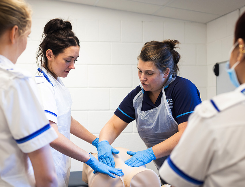 Midwifery students examining model torso