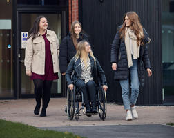 several students are moving towards to the camera. One student is in a wheelchair.