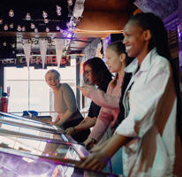 Smiling students are playing on old arcade machines