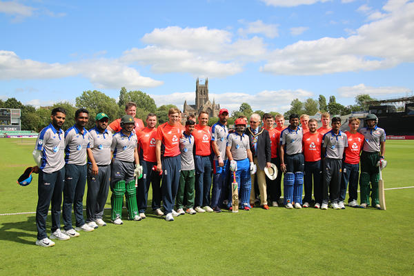 cricketers in blue and red tops with the cathedral in the background
