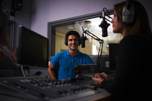 two people either side of a radio desk speaking into microphones