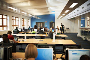 view from the back of a room with rows of desks at which students are working
