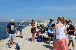 students working in the sun beside a stretch of water