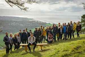 group photo of students with a sea view in the background