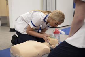 a single female nurse beside a clinical dummy