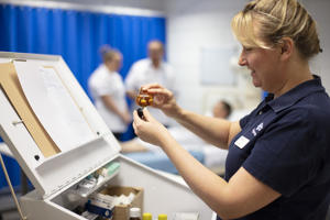 female nurse in a blue uniform beside an opened cabinet