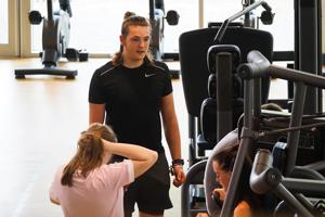 three students beside some gym equipment