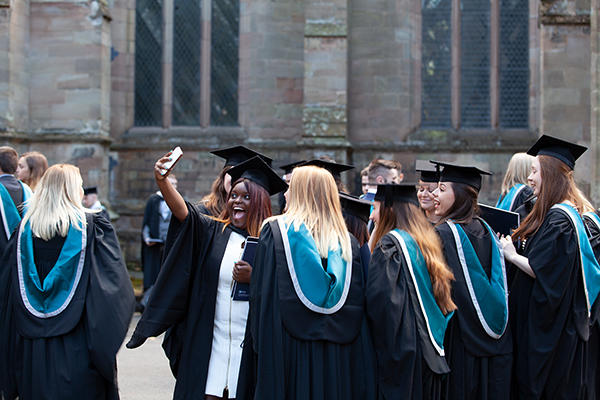 A group of female students celebrating Graduation, including one female student taking a photo of herself