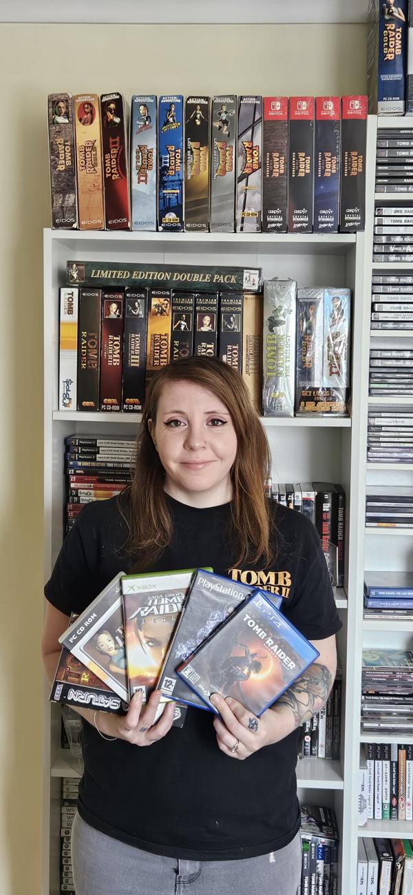 Person holding video games with shelf of video games behind