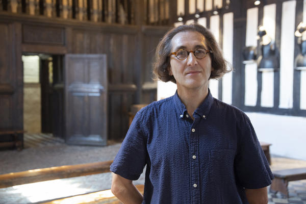 Person standing in a room with wood panelling behind