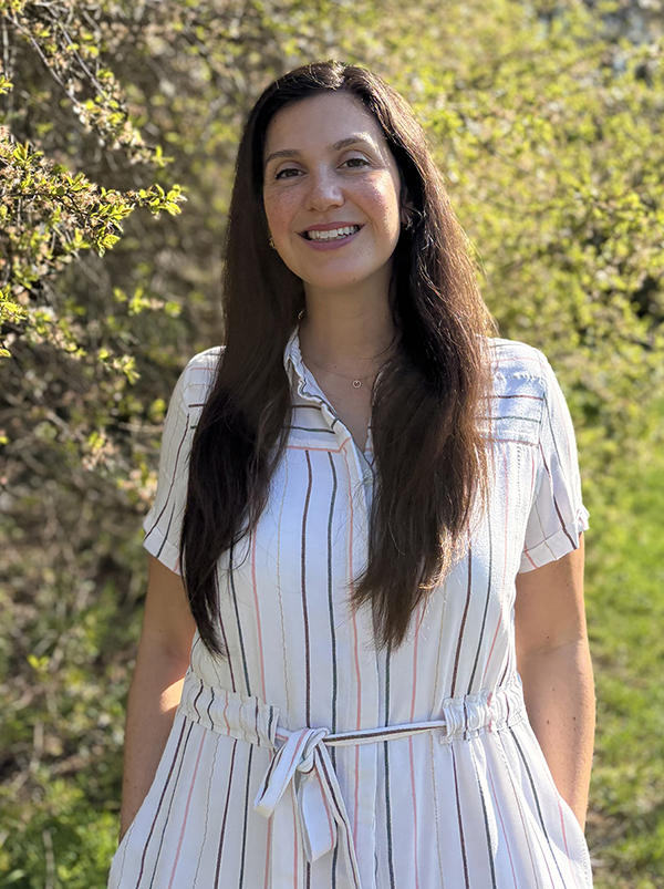 Mary O'Malley standing in front of a green shrub looking at the camera