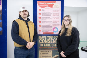 Two people standing either side of two posters