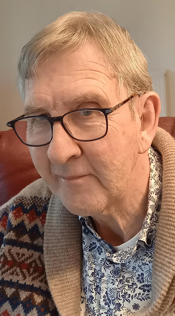 Keith Oliver wearing glasses and a floral shirt, looking at the camera