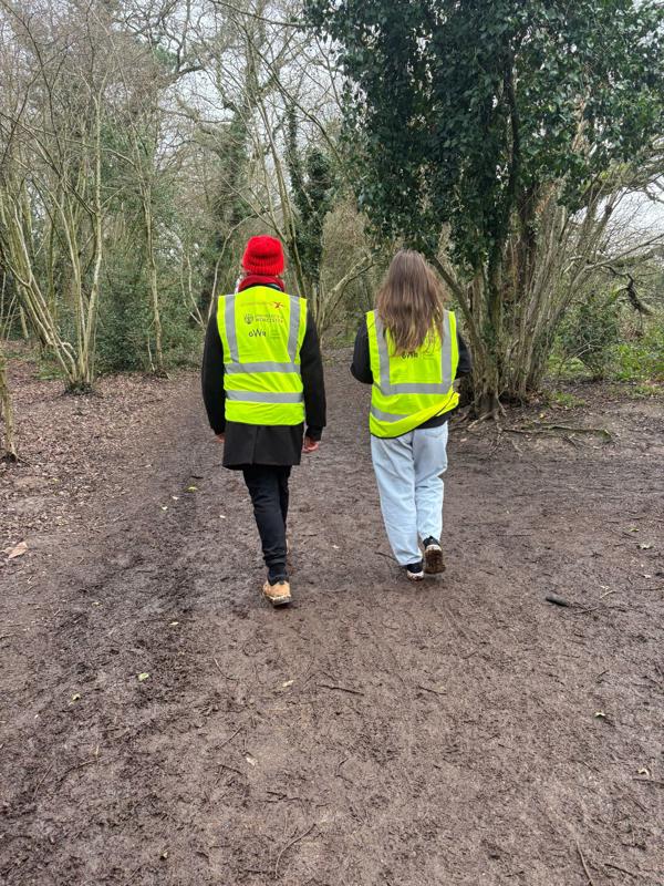 Two people walking away from the camera in a wooded area