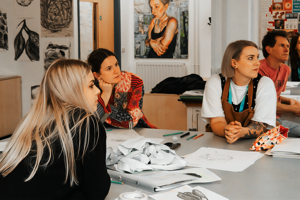 Art students sat around a table with artwork on display