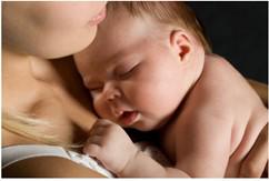 A baby is laying on a woman's chest