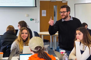 A lecturers is enthusiastically pointing whilst talking to students