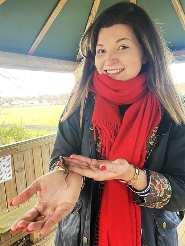 A smiling woman holding a small lizard