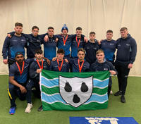 Indoor Cricket Team stood and kneeling for photo, holding the Worcestershire flag