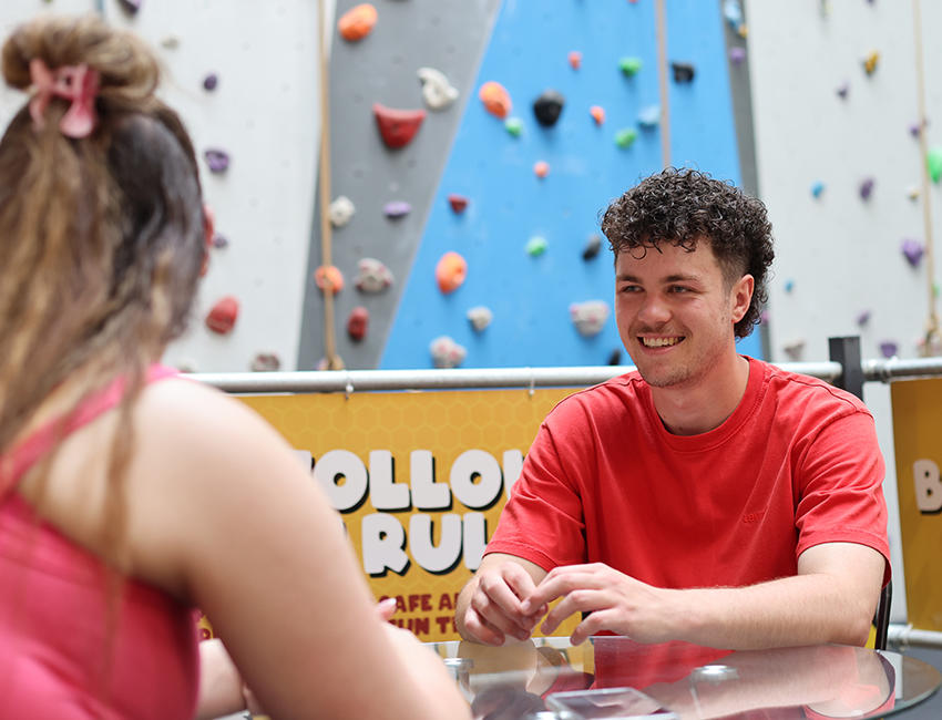 People chatting by a climbing wall