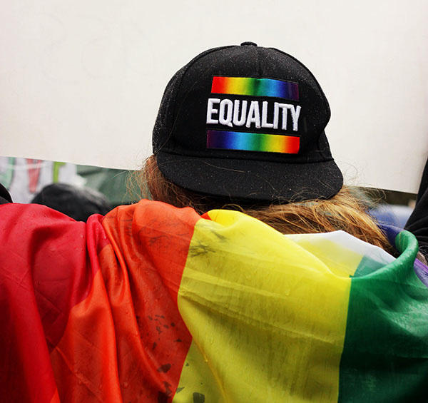 A person, viewed from behind, is wearing a Gay pride hat