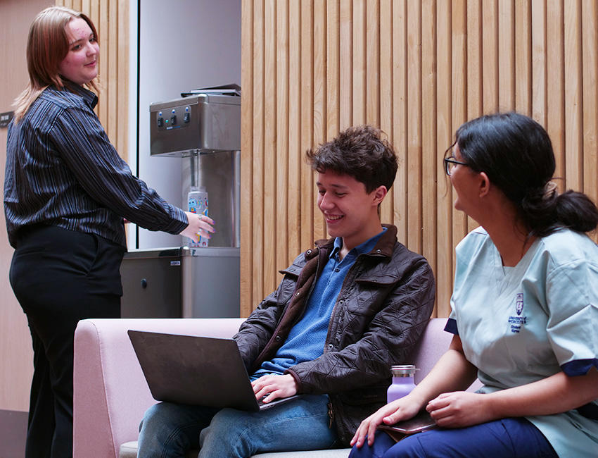 Students sat on sofa talkign to a student using the water fountain