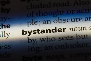 Close-up of the word 'bystander' in bold within a dictionary page under focused light.