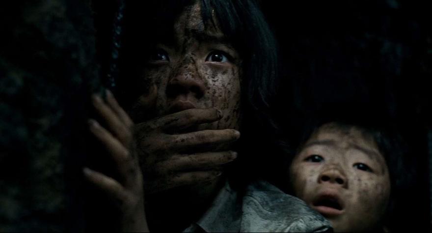 A still from the film The Host featuring two children covered in dirt looking at the camera