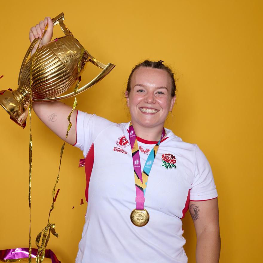 Lark holding up her trophy and smiling. A medal hangs around her neck