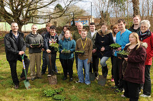 University lectures and students holding spades and plants in a garden