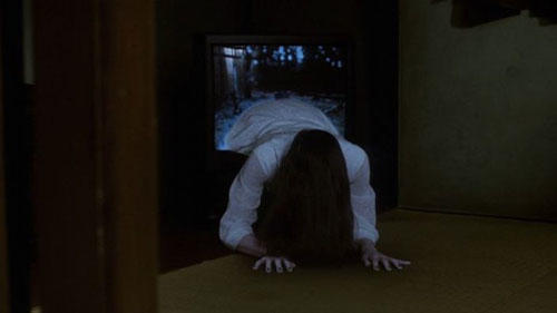 A long haired girl crawls out from inside a television in this film still