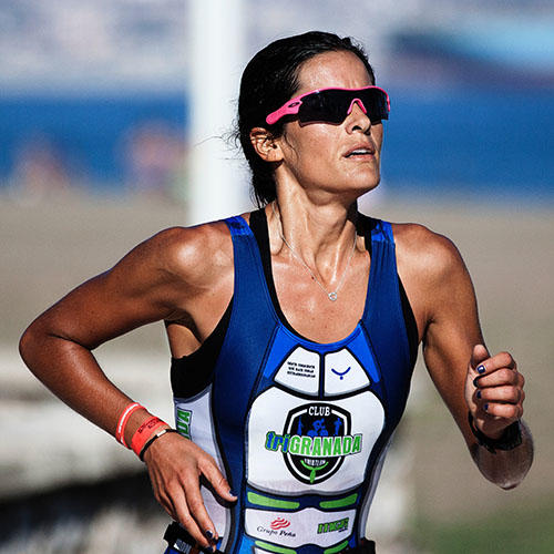 A woman wearing a lycra sport kit and sunglasses running