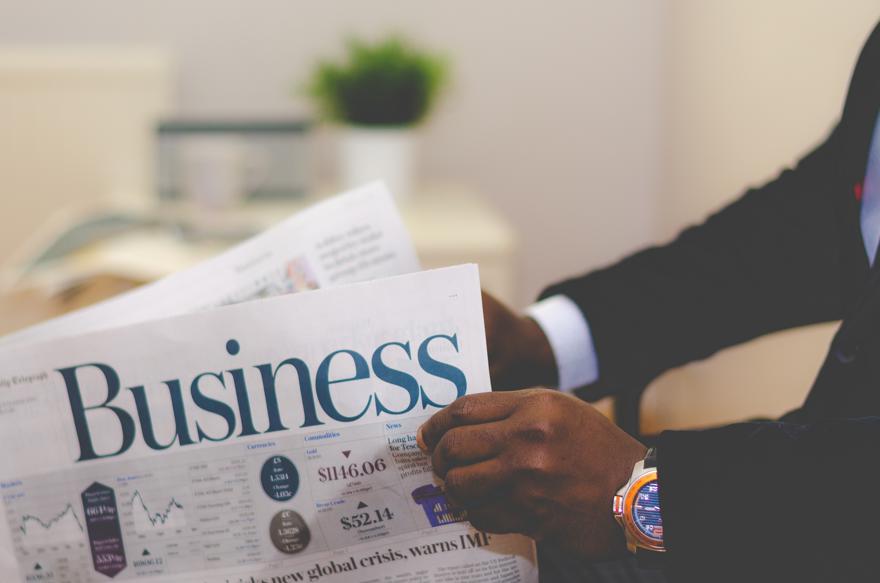 A close up shot of a man's hands reading a business newspaper