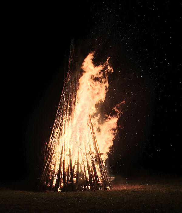 A bonfire is crackling. We can see the timber being used for fuel.