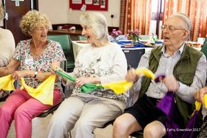 Three older ladies are sitting together and knitting