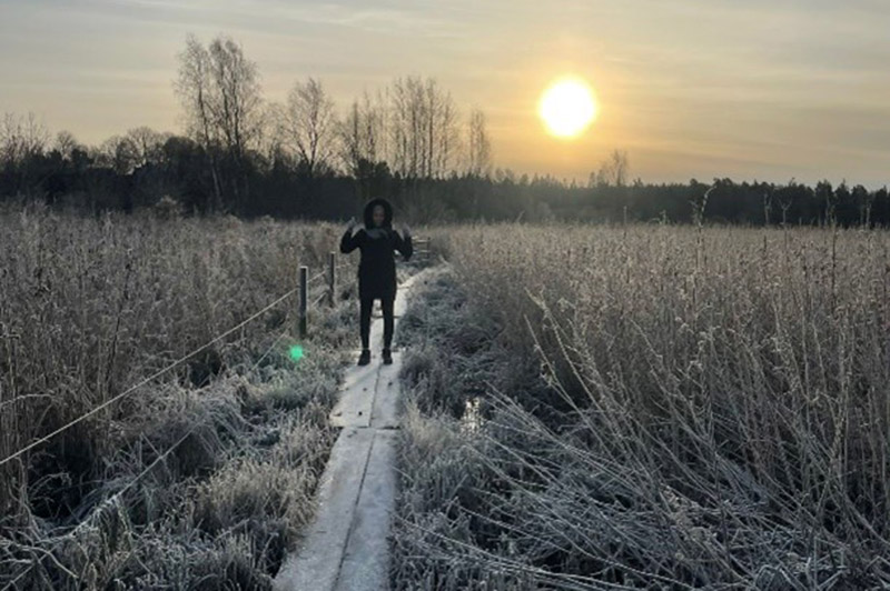 Student in a frozen meadow with the sun in the background