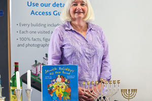 A lady is standing behind a menorah