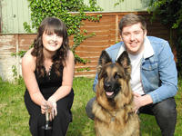 Megan Davis and a man dressed in a denim jacket are sitting in a garden next to an Alsatian dog.