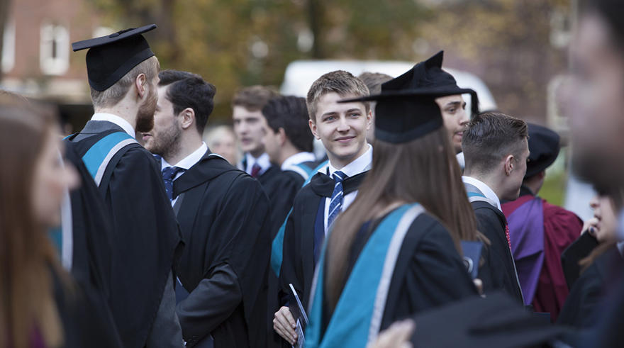 A group of recently graduated students, wearing their robes, are standing together.