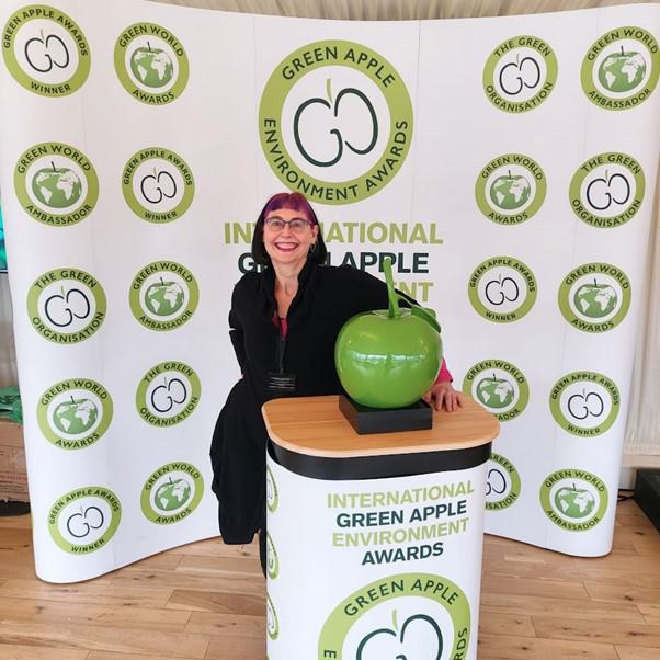 Woman sitting next to apple trophy