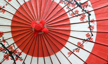 A close up shot of a red and white Japanese umbrella with a printed blossom pattern