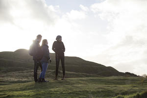 Three students are silhouetted by the sun at the top of the Malvern Hills