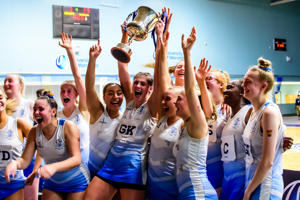 UoW netball players holding up a trophy and cheering