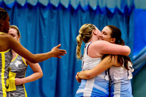 Two netball players hugging after winning a game