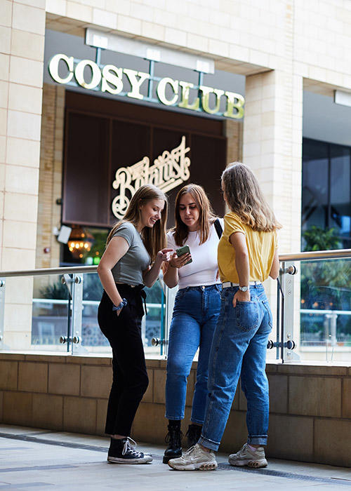 Students looking at mobile phone outside of restaurant